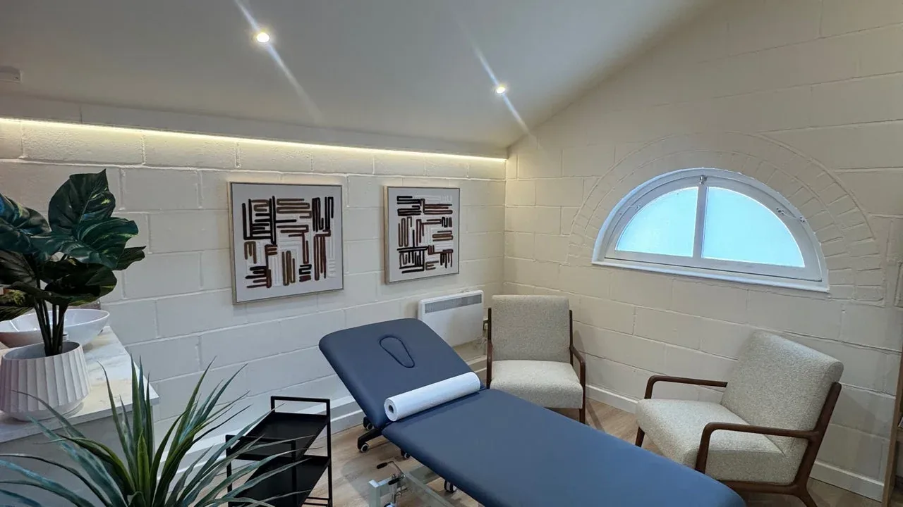 The bright treatment room with a treatment bed and arched window